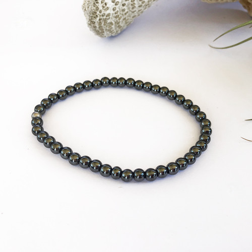 Magnetite Magnetic 4mm bead bracelet on white background with coral behind